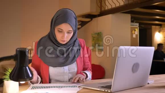 年轻漂亮的穆斯林女商人戴着头巾使用笔记本电脑在跨文化社区工作的特写照片视频的预览图