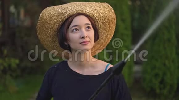 亚洲女人穿着草帽用水管浇树视频的预览图
