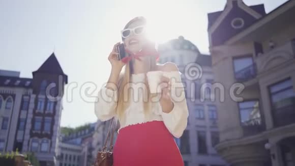 时尚女青年站在街上晒太阳用手机说话天气晴朗的女孩视频的预览图