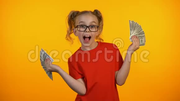 可爱的快乐女孩展示了一大堆美元现金一钱的获奖赠款收入视频的预览图