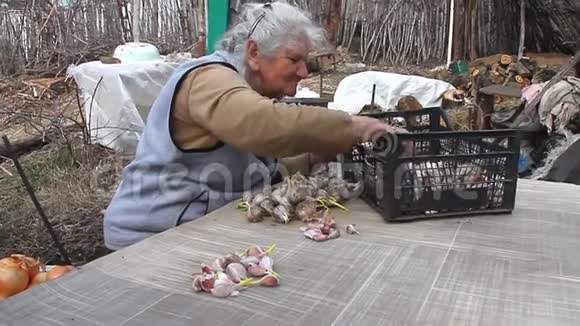 一位白发苍苍的老妇人在街上做饭或种植大蒜之前拿起并清洗大蒜生活在一个古老的农场里视频的预览图