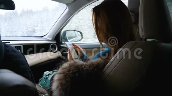 一个年轻的女人在坐在汽车前乘客座位上时使用手机视频的预览图