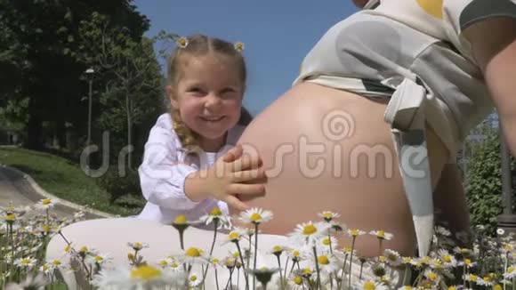 在公园的花丛中怀着女儿的孕妇视频的预览图