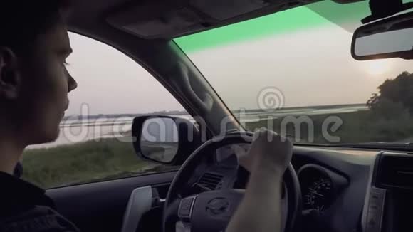 一个迷人的家伙开着一辆大轿车背景是一个美丽的日落男子在乡村旅行视频的预览图