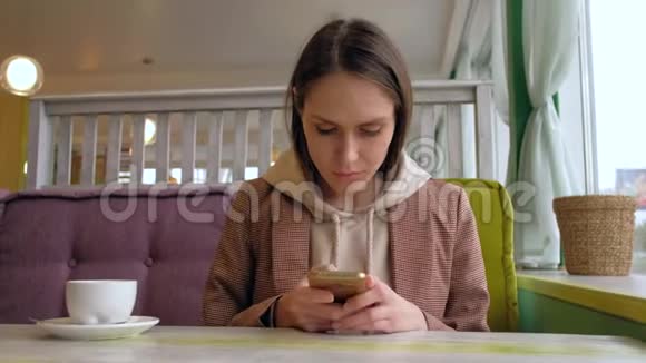 女性在咖啡馆里使用智能手机视频的预览图