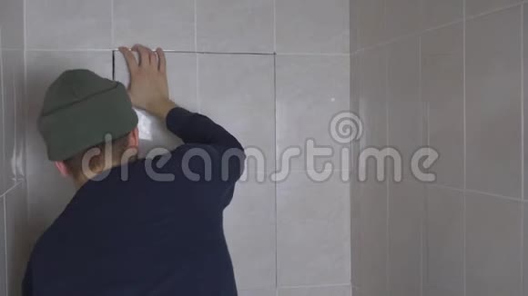 一个年轻人因水管漏水而从浴室的瓷砖上掉下来视频的预览图