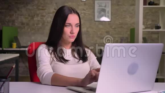 布鲁内的女人获得了一个洞察力并开始在办公室的笔记本电脑上积极打字视频的预览图