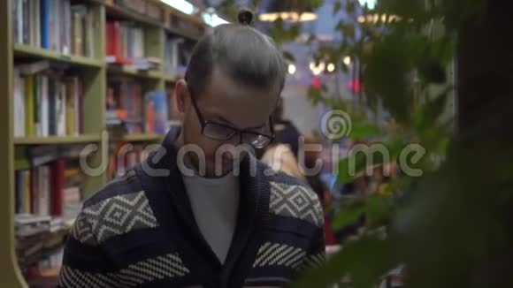 一个人在书店里研究一本书修直眼镜视频的预览图