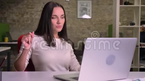 Brunnete女士坐在笔记本电脑前看着屏幕开始全神贯注地在座位上跳舞唱歌视频的预览图