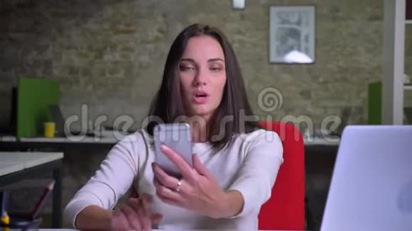 女人用智能手机通过视频聊天展示办公室背景挥手道别视频的预览图