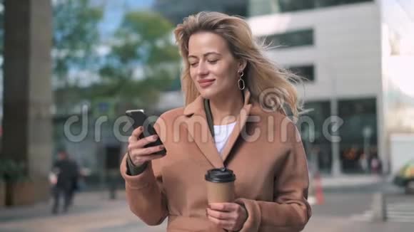 美丽的金发女人在街上用咖啡网冲浪视频的预览图