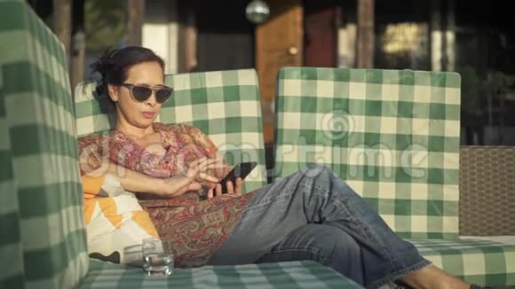 亚洲中年妇女在智能手机和饮用水上上网视频的预览图