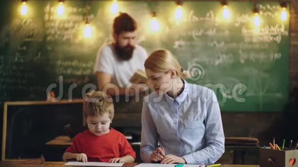 老师和小男孩在绿板和胡子教授的背景上画画和交谈回到学校背景视频的预览图