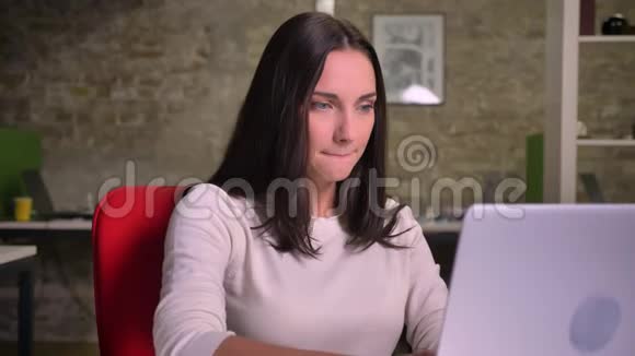 女商人在笔记本电脑前看着屏幕紧张地咬着嘴唇让她的手指交叉希望视频的预览图