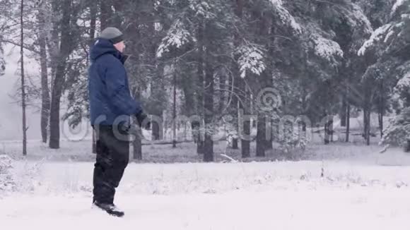 一个快乐的女孩跑到一个男人身边跳上他在冬天的森林或公园里吻他可爱的一对在冬天放松视频的预览图