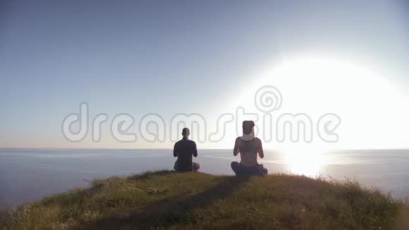 控制精神青年男女坐在山顶看海坐在莲花的位置上沉思视频的预览图