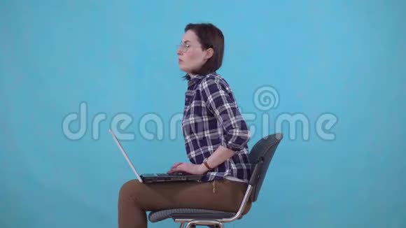 坐在笔记本电脑上工作的女人正在经历痔疮带来的疼痛和不适视频的预览图