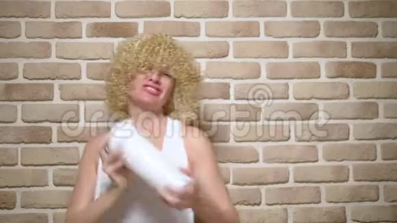 快乐开朗留着白色卷发的女孩在砖墙背景上摇着摇床复制空间视频的预览图