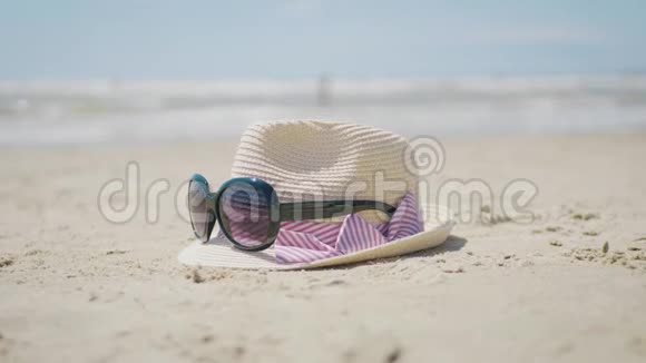 沙滩上戴草帽和太阳镜的暑假概念带帽子和眼镜的海滩背景假日视频的预览图
