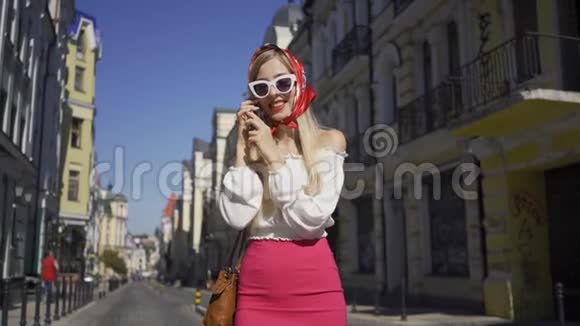 站在街上用手机说话的漂亮年轻女人迷人的时尚女孩在阳光明媚的日子里享受阳光视频的预览图