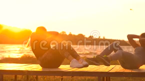 两个年轻漂亮的女孩在日出或日落前在海边的沙滩上脱衣服视频的预览图