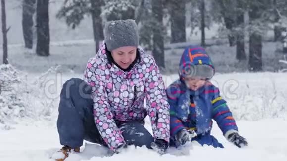 快乐的妈妈和宝宝在一个下雪的公园里玩耍把雪扔进相机里另外家庭关系户外视频的预览图