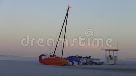黄昏时沙滩上的红色双体帆船视频的预览图