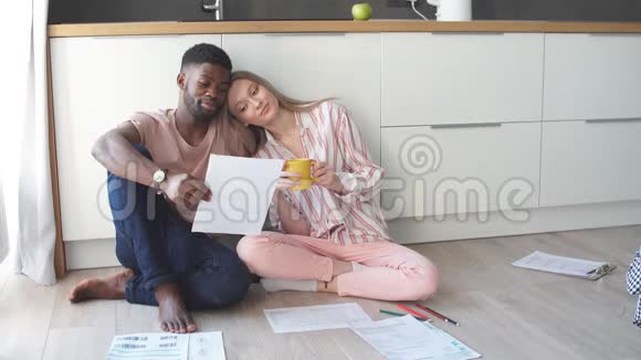 一对夫妇在家里做家庭预算会计坐在厨房地板上视频的预览图