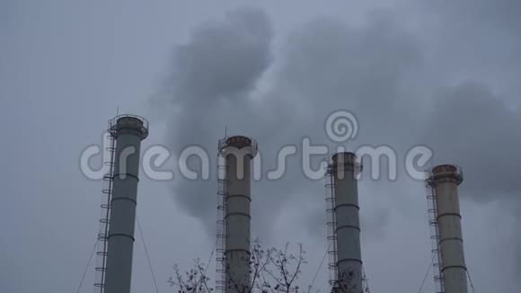 灰蒙蒙的天空背景下的烟雾工业管道烟从植物的烟囱里冒出来顶着灰色的天空环境视频的预览图