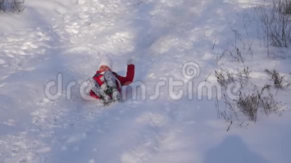快乐的女孩骑着雪橇从高雪滑梯和笑声冬天在圣诞公园休息的女孩视频的预览图