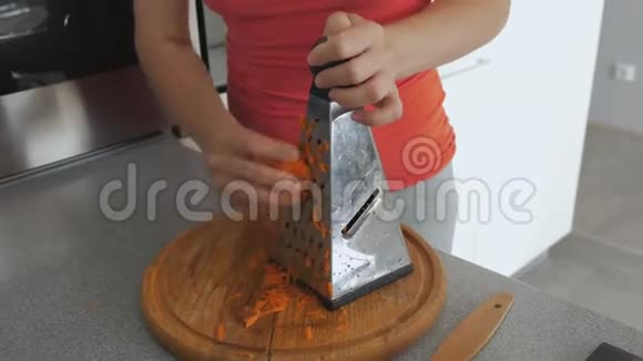 厨房里的女家庭主妇把胡萝卜揉在蔬菜的烤架上视频的预览图