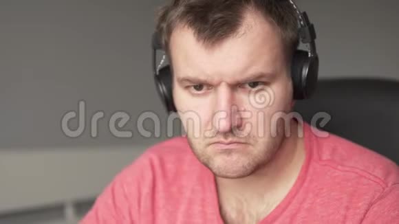 一个戴着耳机的严肃男人坐在电脑前的椅子上视频的预览图