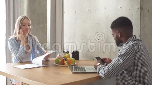 年轻的多民族夫妇坐在厨房对面规划概念视频的预览图