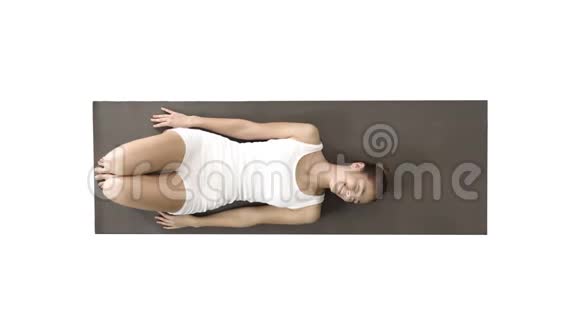 瑜伽女人笑着躺在白色背景的地板上视频的预览图