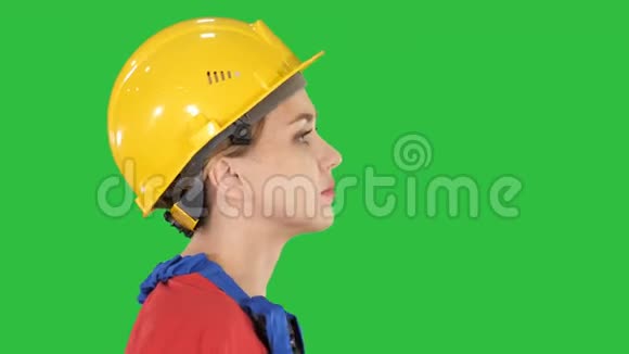 年轻的女工程师带着黄色的安全帽在绿色的屏幕上行走和微笑铬钥匙视频的预览图
