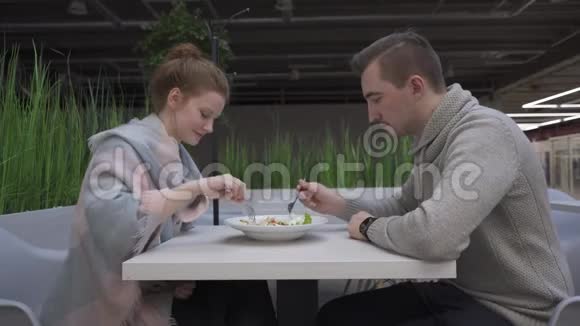 年轻漂亮的女人和男人正在咖啡馆里吃凯撒沙拉视频的预览图