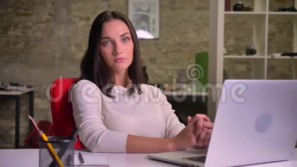 在办公室工作的女人在笔记本电脑前认真地看着镜头视频的预览图