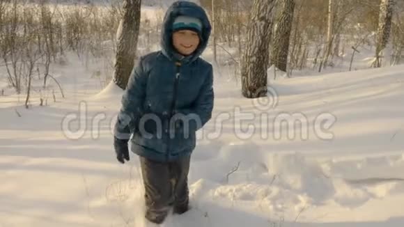 无忧无虑的少年男孩在雪地里漂流冬天在雪地里散步视频的预览图