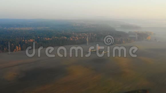 在史诗般的秋野和被夕阳薄雾覆盖的森林上空飞翔的无人机朝着雾蒙蒙的天际线飞去宁静的田园自然视频的预览图