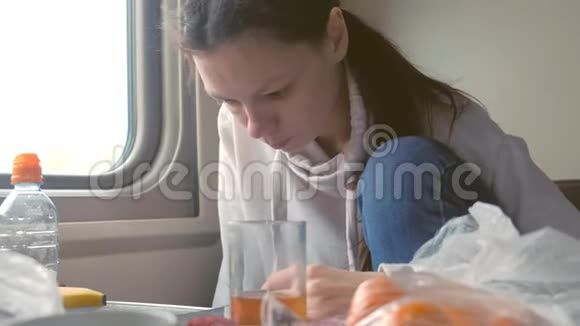 疲惫的女人坐着二等车厢坐火车在电话里吃和看新闻视频的预览图