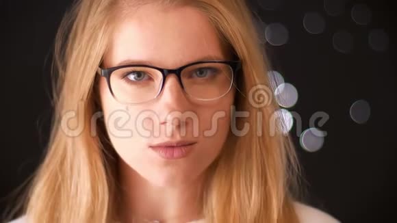 戴着漂亮眼镜的白种人放松的女孩一边自信地摸着眼镜一边用照相机看着镜头视频的预览图