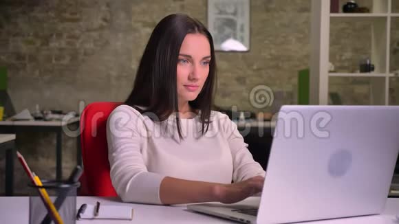 在办公室工作的女人在笔记本电脑前对着镜头微笑视频的预览图