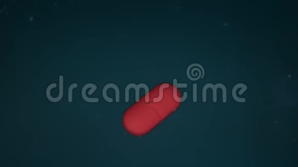 红色药丸或片剂在蓝色背景下液体中溶解的过程时间推移视频的预览图