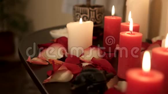 按摩院玫瑰花瓣中燃烧蜡烛的特写视频的预览图