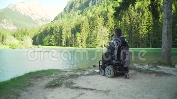 在森林和山地附近的美丽湖泊中残疾渔民乘坐电动轮椅捕鱼的4K分辨率视频的预览图