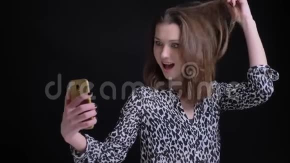 年轻漂亮的高加索女人在电话里自拍并做出兴奋的面部表情的特写照片视频的预览图