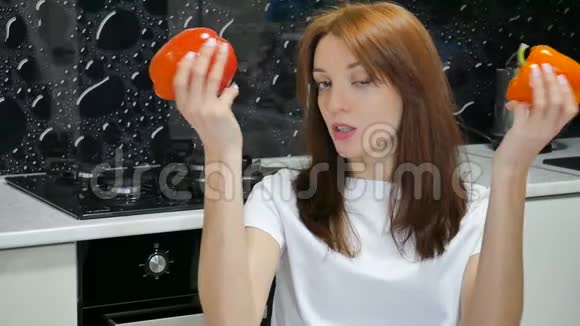 快乐兴奋的年轻女人在厨房准备食物之前玩红甜椒和橘子甜椒积极的人视频的预览图