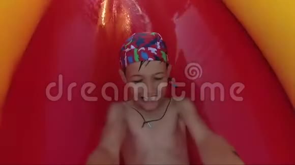 暑假期间快乐可爱的小男孩滑下水上滑梯视频的预览图