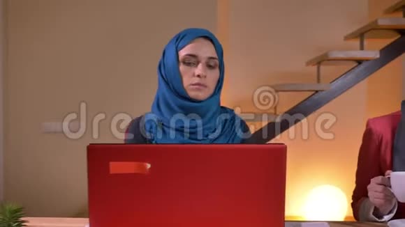 两位成功的阿拉伯年轻女性办公室工作人员在工作场所用手提电脑打字的照片特写视频的预览图