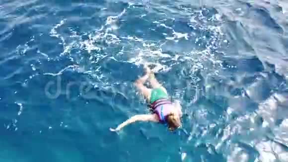 穿泳衣的年轻女人在浮潜面罩和管子里游泳女孩浮潜和观看珊瑚礁和热带鱼在红海视频的预览图